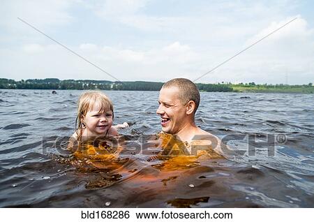 Stock Photograph - Caucasian father and daughter swimming in lake. Fotosearch