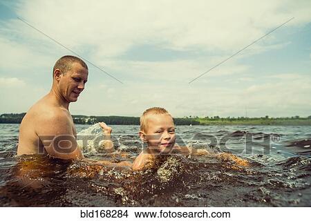 Picture - Caucasian father and son swimming in lake. Fotosearch