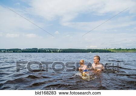 Stock Image - Caucasian father and son swimming in lake. Fotosearch