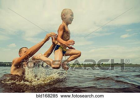 Stock Photography - Caucasian father and son swimming in lake. Fotosearch