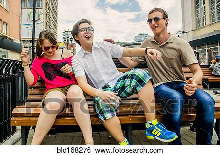 Caucasian friends playing on city bench View Large Photo Image Stock Photograph - Caucasian friends playing on city bench. Fotosearch