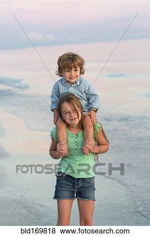 Caucasian girl carrying brother on shoulders on beach View Large Photo Image Stock Photo - Caucasian girl carrying brother on shoulders on beach. Fotosearch