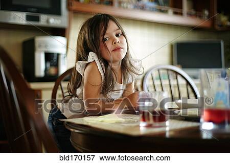 Stock Photo - Caucasian girl eating at kitchen table. Fotosearch