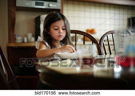 Stock Photograph - Caucasian girl eating at kitchen table. Fotosearch