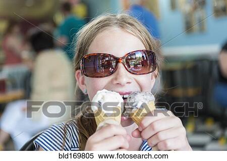 Stock Photography - Caucasian girl eating two ice cream cones. Fotosearch