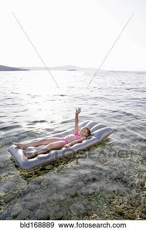 Stock Photo - Caucasian girl floating on raft in lake. Fotosearch
