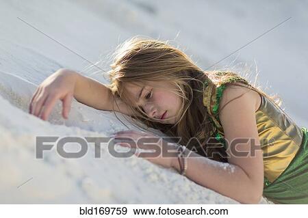 Stock Photo - Caucasian girl laying on desert sand dune. Fotosearch