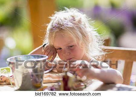 Stock Image - Caucasian girl playing with dolls at table. Fotosearch