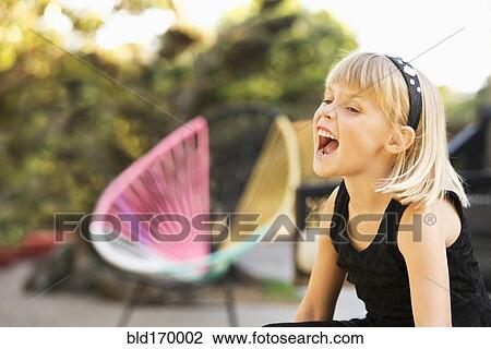 Stock Image - Caucasian girl shouting in backyard. Fotosearch