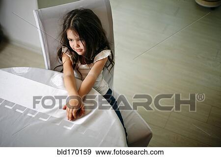 Stock Photo - Caucasian girl sitting at table. Fotosearch