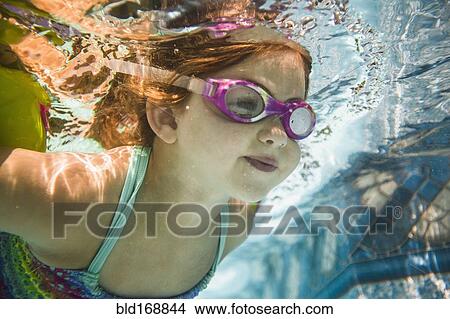 Picture - Caucasian girl swimming underwater in swimming pool. Fotosearch