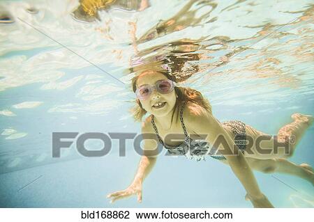 Stock Image - Caucasian girl swimming underwater in swimming pool. Fotosearch