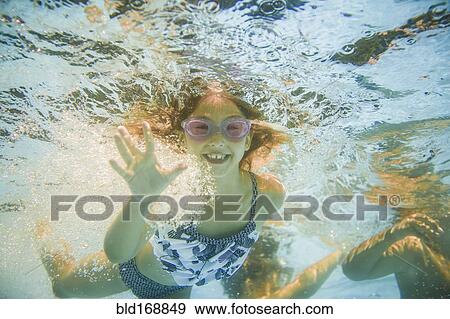 Stock Photo - Caucasian girl swimming underwater in swimming pool. Fotosearch