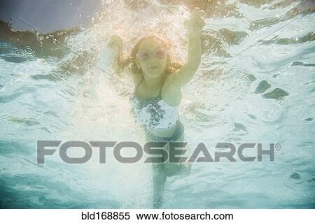 Stock Photography - Caucasian girl swimming underwater in swimming pool. Fotosearch