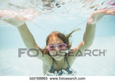 Stock Photography - Caucasian girl swimming underwater in swimming pool. Fotosearch