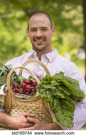 Caucasian man carrying basket of fresh produce View Large Photo Image Picture - Caucasian man carrying basket of fresh produce. Fotosearch