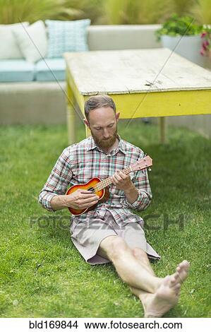 Caucasian man playing ukulele in backyard View Large Photo Image Picture - Caucasian man playing ukulele in backyard. Fotosearch