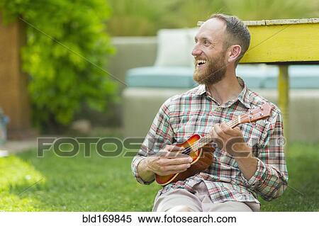 Caucasian man playing ukulele in backyard View Large Photo Image Stock Photography - Caucasian man playing ukulele in backyard. Fotosearch