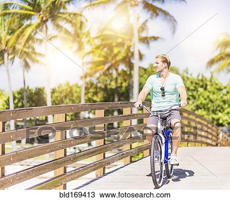 Caucasian man riding bicycle on bridge View Large Photo Image Stock Image - Caucasian man riding bicycle on bridge. Fotosearch