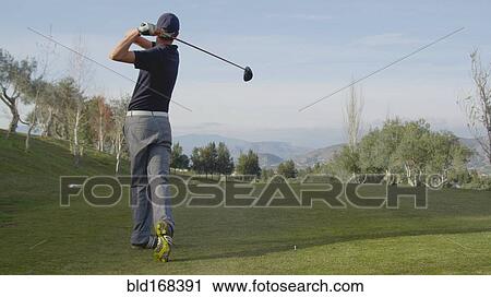 Stock Image - Caucasian man teeing off on golf course. Fotosearch