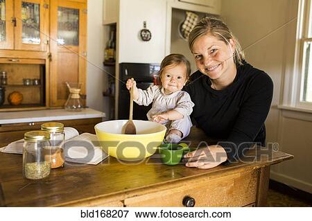 Stock Photo - Caucasian mother and baby girl baking in kitchen. Fotosearch
