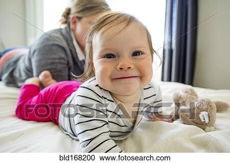 Caucasian mother and baby girl laying on bed View Large Photo Image Stock Image - Caucasian mother and baby girl laying on bed. Fotosearch