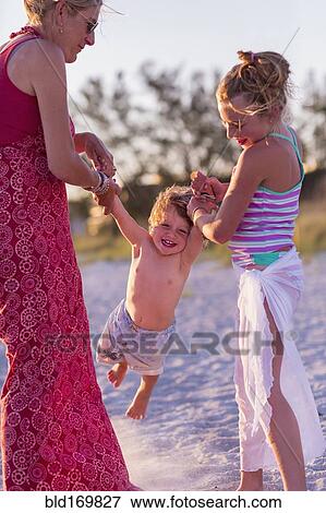 Stock Photo - Caucasian mother and children playing on beach. Fotosearch