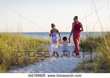 Stock Photograph - Caucasian mother and children walking on beach. Fotosearch
