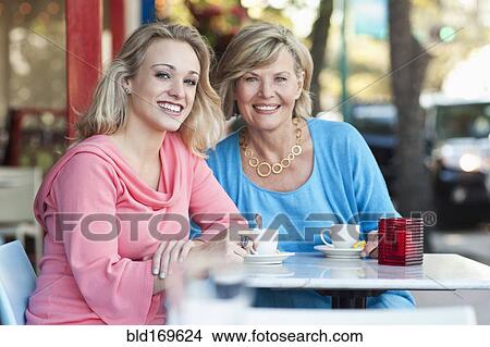 Picture - Caucasian mother and daughter drinking coffee at sidewalk cafe. Fotosearch
