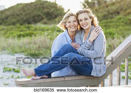 Stock Photography - Caucasian mother and daughter hugging on beach. Fotosearch