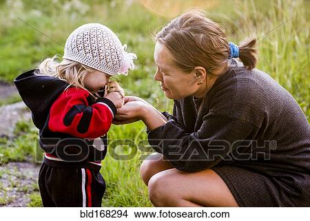 Picture - Caucasian mother and daughter playing with chick in garden. Fotosearch