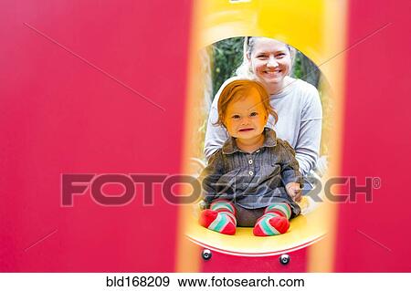 Stock Photo - Caucasian mother and daughter playing at playground. Fotosearch