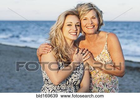 Stock Photo - Caucasian mother and daughter smiling on beach. Fotosearch
