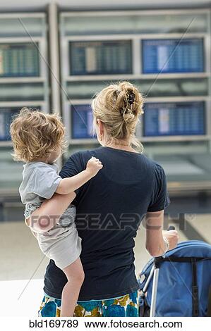 Caucasian mother carrying son in airport View Large Photo Image Stock Photo - Caucasian mother carrying son in airport. Fotosearch