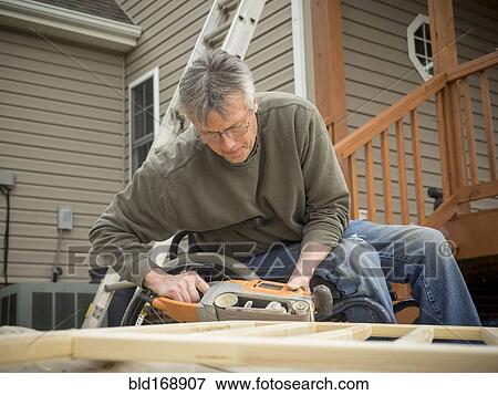 Stock Photo - Caucasian paraplegic man wood working in backyard. Fotosearch