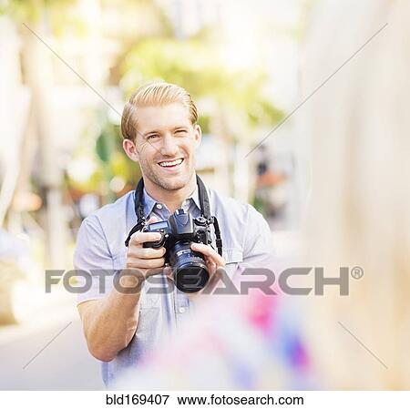Stock Photo - Caucasian photographer photographing woman outdoors. Fotosearch