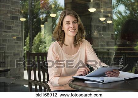 Stock Image - Caucasian student using digital tablet at cafe. Fotosearch
