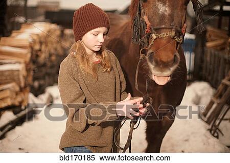 Stock Photography - Caucasian teenage girl leading horse in snowy field. Fotosearch