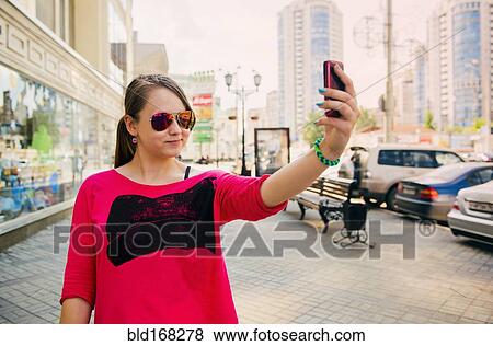 Stock Photo - Caucasian teenage girl taking self portrait on cell phone. Fotosearch