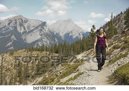 Stock Image - Caucasian woman hiking on remote hillside. Fotosearch