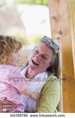 Picture - Caucasian woman holding grandson in rocking chair. Fotosearch