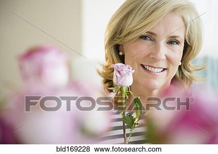 Caucasian woman holding pink rose View Large Photo Image Stock Photo - Caucasian woman holding pink rose . Fotosearch