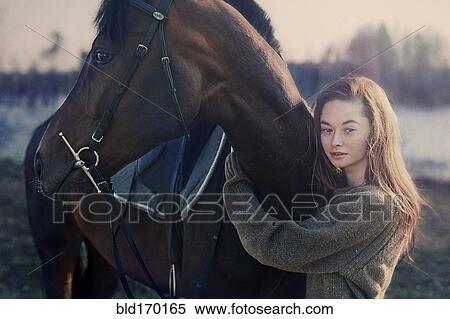 Stock Photography - Caucasian woman hugging horse in field. Fotosearch