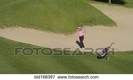 Stock Photo - Caucasian woman in sand trap on golf course. Fotosearch