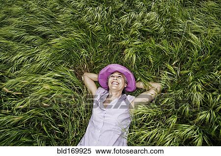 Stock Photography - Caucasian woman laying in tall grass. Fotosearch