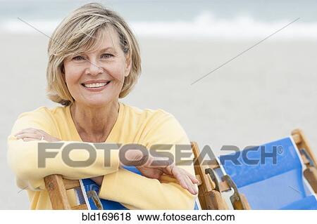 Caucasian woman leaning on deck chair on beach View Large Photo Image Stock Photo - Caucasian woman leaning on deck chair on beach. Fotosearch