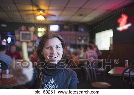 Stock Image - Caucasian woman offering french fry in bar. Fotosearch
