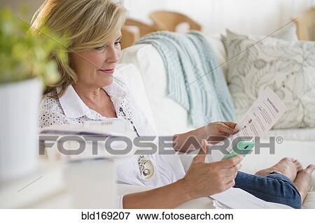Stock Photo - Caucasian woman paying bills online on cell phone. Fotosearch