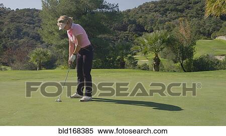 Stock Photography - Caucasian woman putting on golf course. Fotosearch
