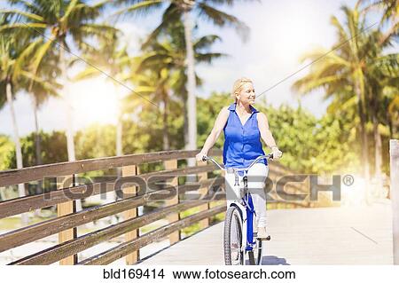 Picture - Caucasian woman riding bicycle on bridge. Fotosearch